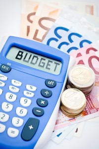 Calculatrice indiquant le mot "budget" posée sur des billets de banque
